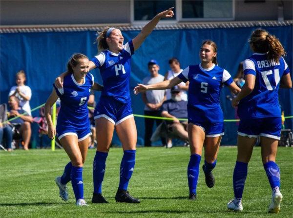 Members of the women's soccer team celebrate a play. 